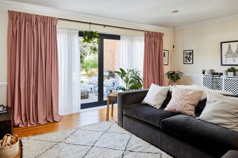 A living room with large bi fold doors dressed with pink curtains and white voiles