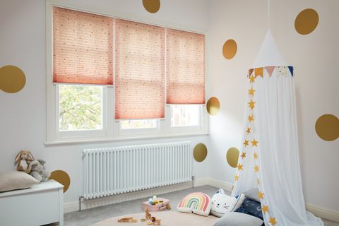 Gold dot-print on a pale pink/peach Pleated blinds dressed on windows of kids' room.