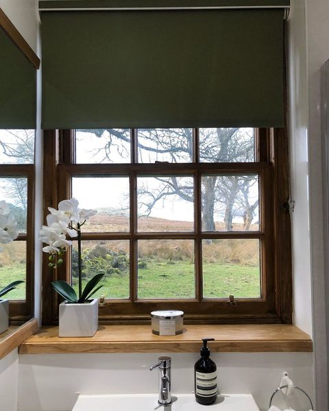 Green roller blind dressed on window of bathroom