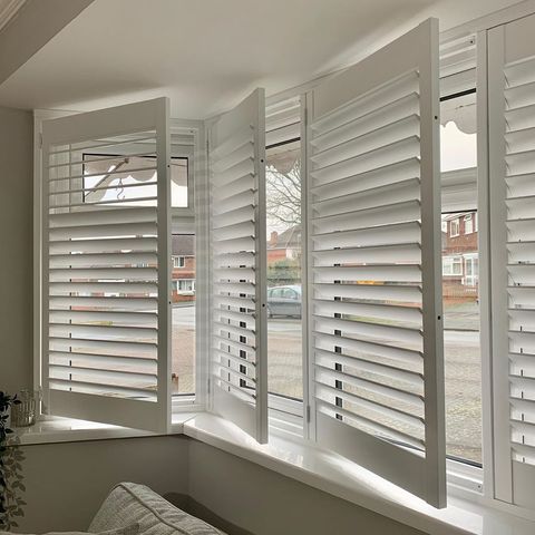 White full height shutters opened on living room window