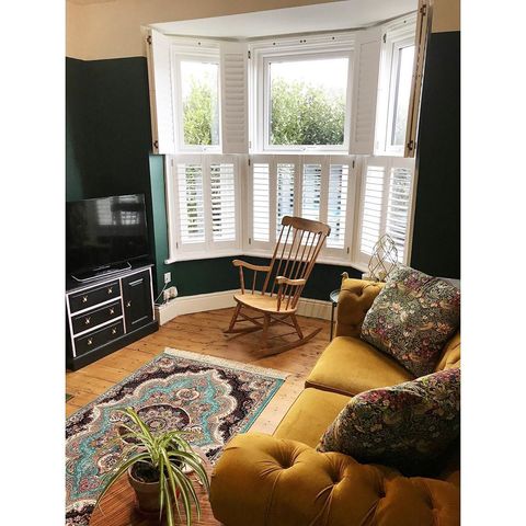 White Tier on Tier shutters behind rocking chair and mustard velvet sofa