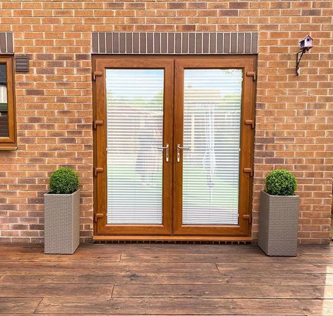 white venetian blinds shut behind brown, glass patio doors onto decking