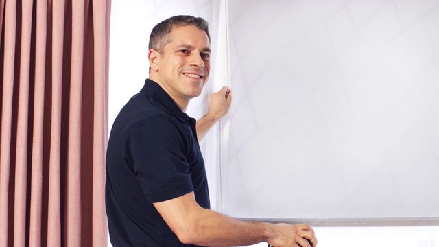 Advisor close up smiling holding blind cord with blush pink curtains next to him