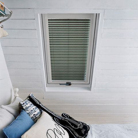 Barely Black Skylight Venetian blinds on single room window in a loft bedroom. The blinds are black and compliment the white coloured wall.