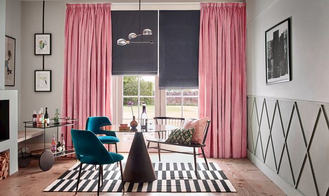 Velvet rose pink curtains over a dark roman blind in a modern, bright living room