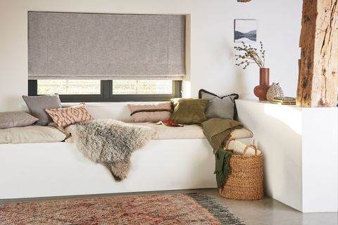 Nest Pewter roman blind in a bedroom with a blanket and throw pillows on the bed