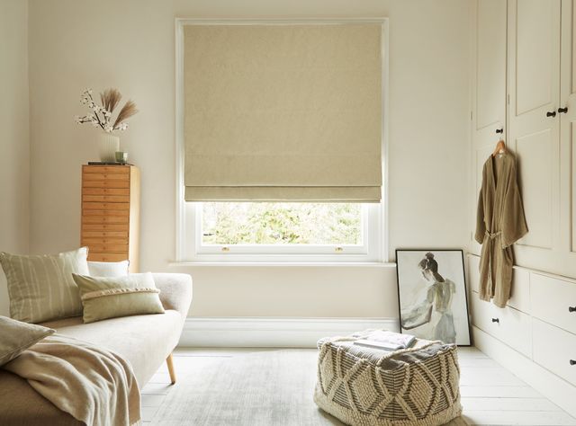 Serene Wasabi in a white room with a cream sofa on the left and a wardrobe with a dress hanging up on the right