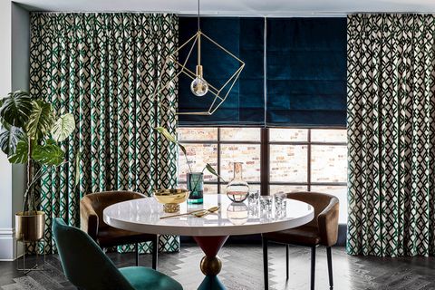 emerald and gold curtains on a large window paired with teal roman blinds in a dining room