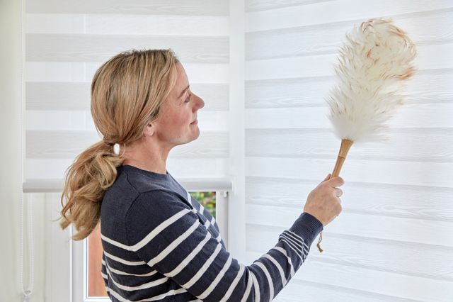 woman cleaning white day & night roller blinds with duster