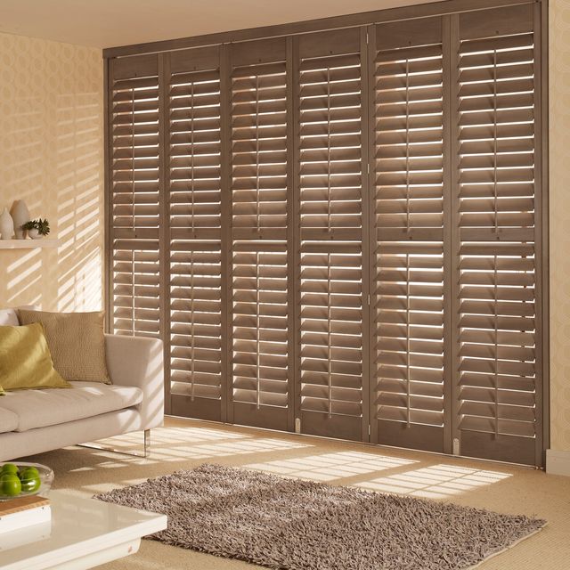 antique oak dark brown wooden tracked shutters on a living room window