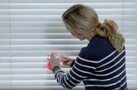 woman cleaning wooden blinds