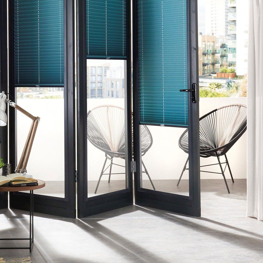 close up of torocca blue perfect fit pleated blinds on half open bi fold doors leading out to patio area