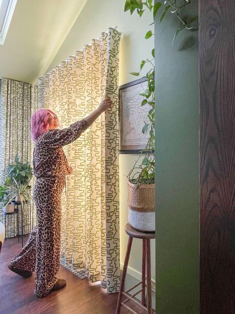 A-woman-in-leopard-print-pants-hangs-curtains-in-the-dining-room-of-Kiwi-Curtain